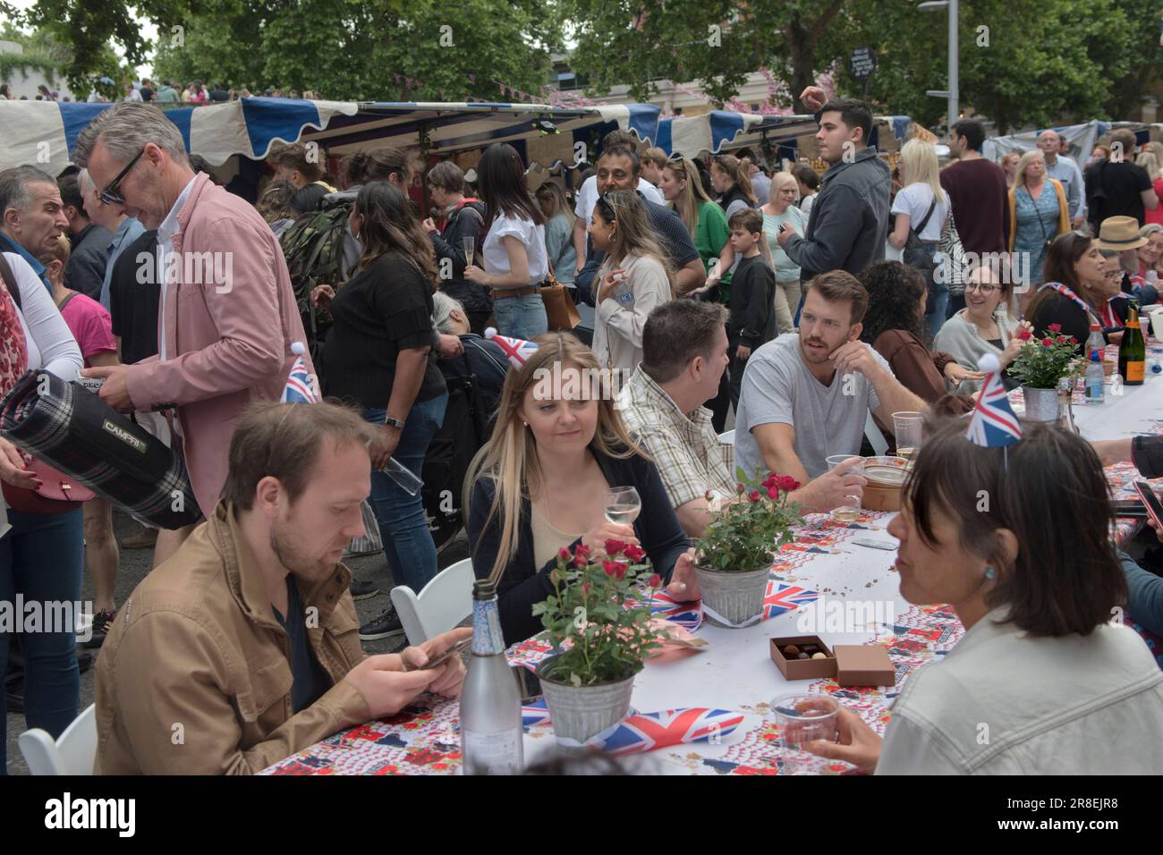 Chelsea, London, England 4th June 2022. The Kings Road, Platinum Jubilee Street Party, that is supporting the British Red Cross Ukraine crisis appeal. The Kings Road is in part closed to traffic, tables run down the centre of the road, food stalls are set up and doing good business. Local Chelsea and Knightsbridge young adults, chat and drink Champagne. Stock Photo