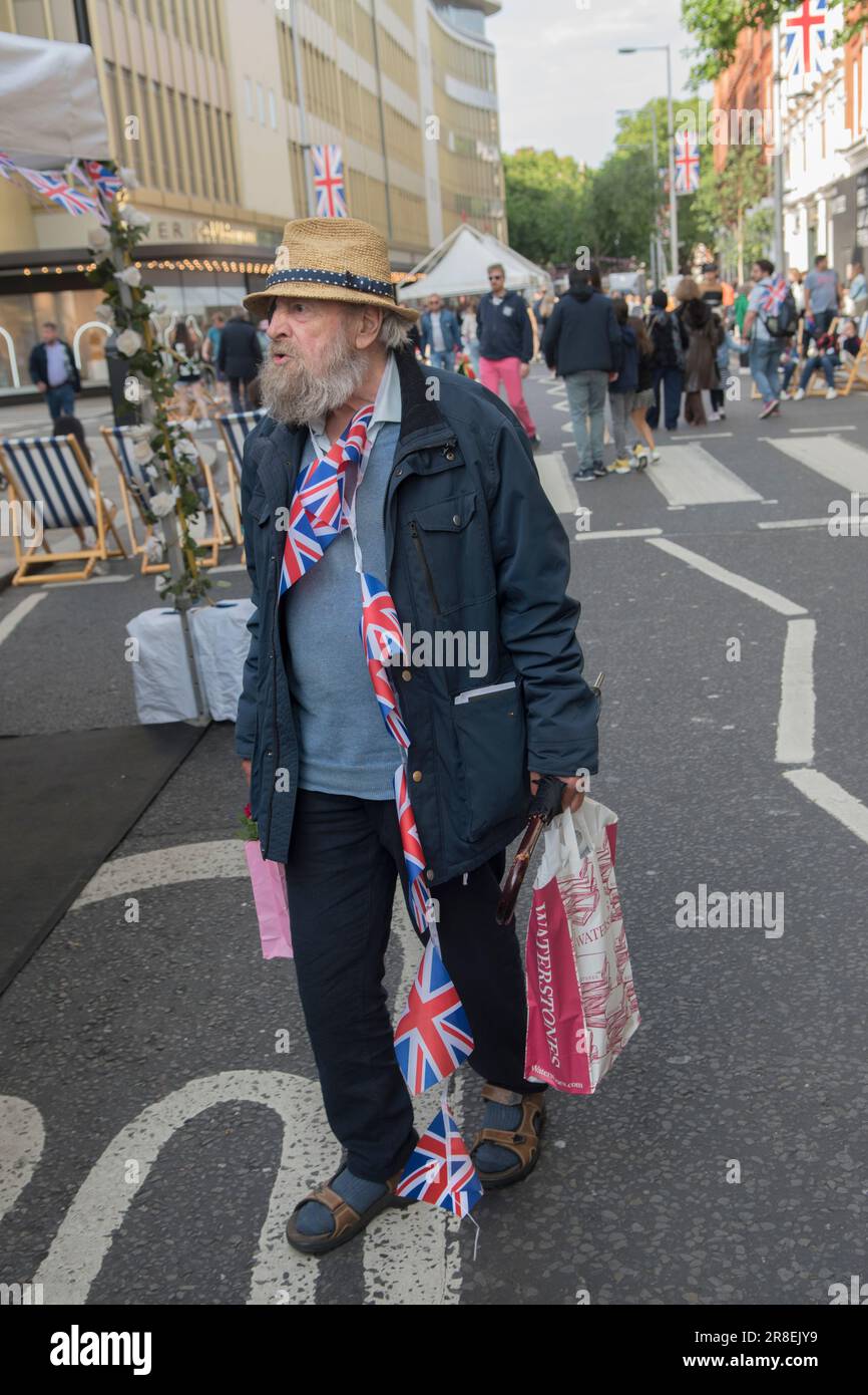 The Kings Road, Platinum Jubilee Street Party, that is supporting the British Red Cross Ukraine crisis appeal. The Kings Road is in part closed to traffic. An older man, a resident with bunting around his neck wanders down the road, slightly worse for wear - drunk. Chelsea, London, England 4th June 2022. 2020s UK HOMER SYKES Stock Photo