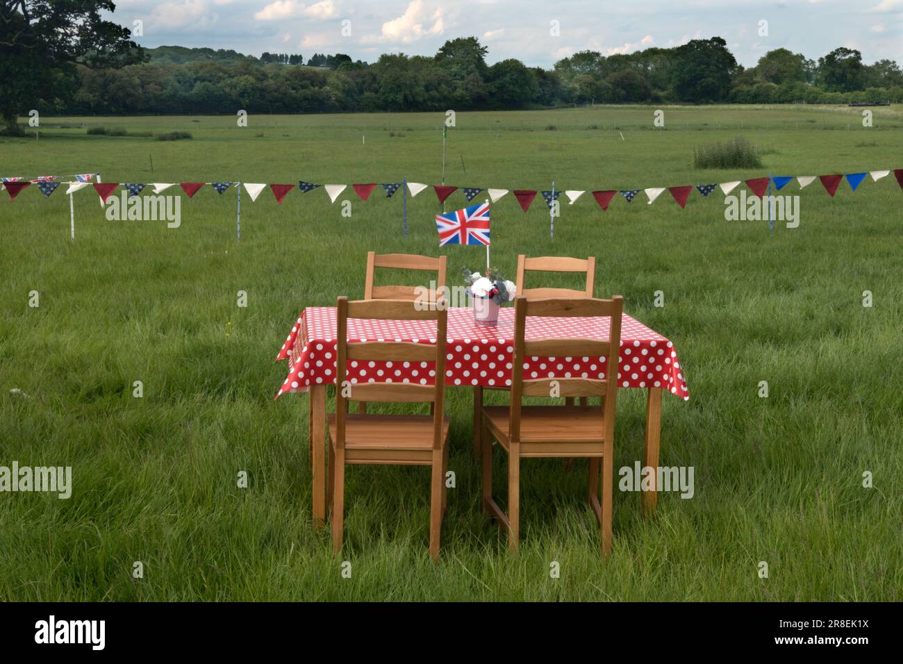 Picnic table in a field Union Jack flag, bunting. Queen Elizabeth II Platinum Jubilee celebrations. Villagers prepare for a communal evening meal to mark the Queen's 70 years on the throne. Theddingworth, Leicestershire, England 2nd June 2022. 2020s UK HOMER SYKES Stock Photo