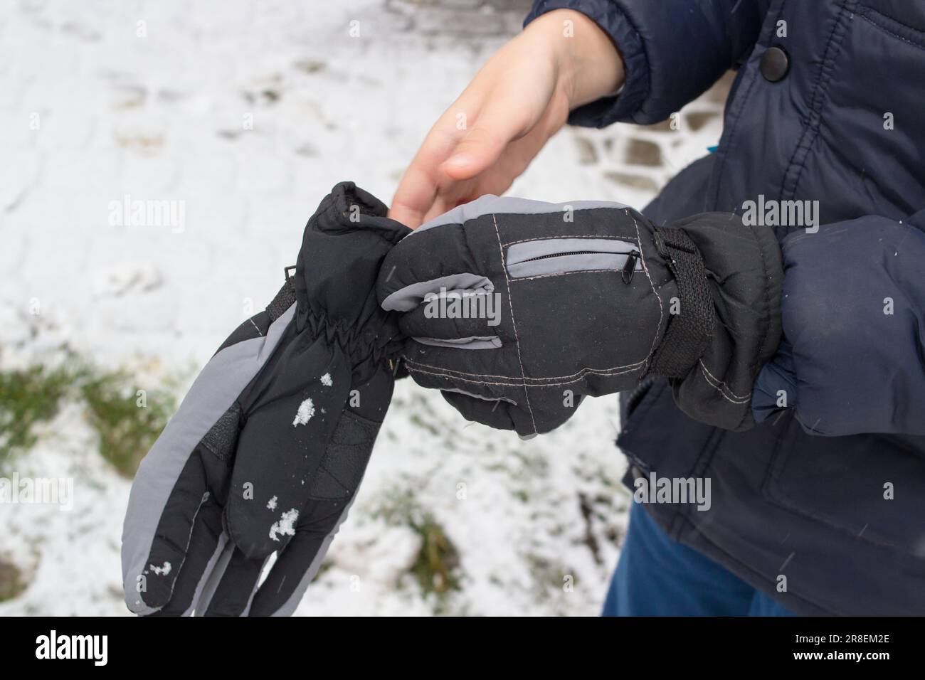 a young boy put on gloves in his hands in the winter Stock Photo