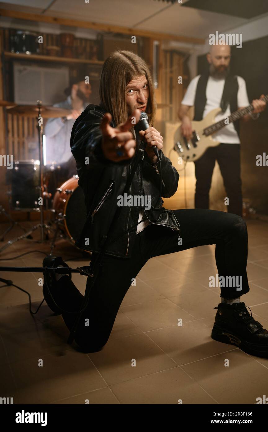 Male singer practice singing on microphone while training with his rock band Stock Photo