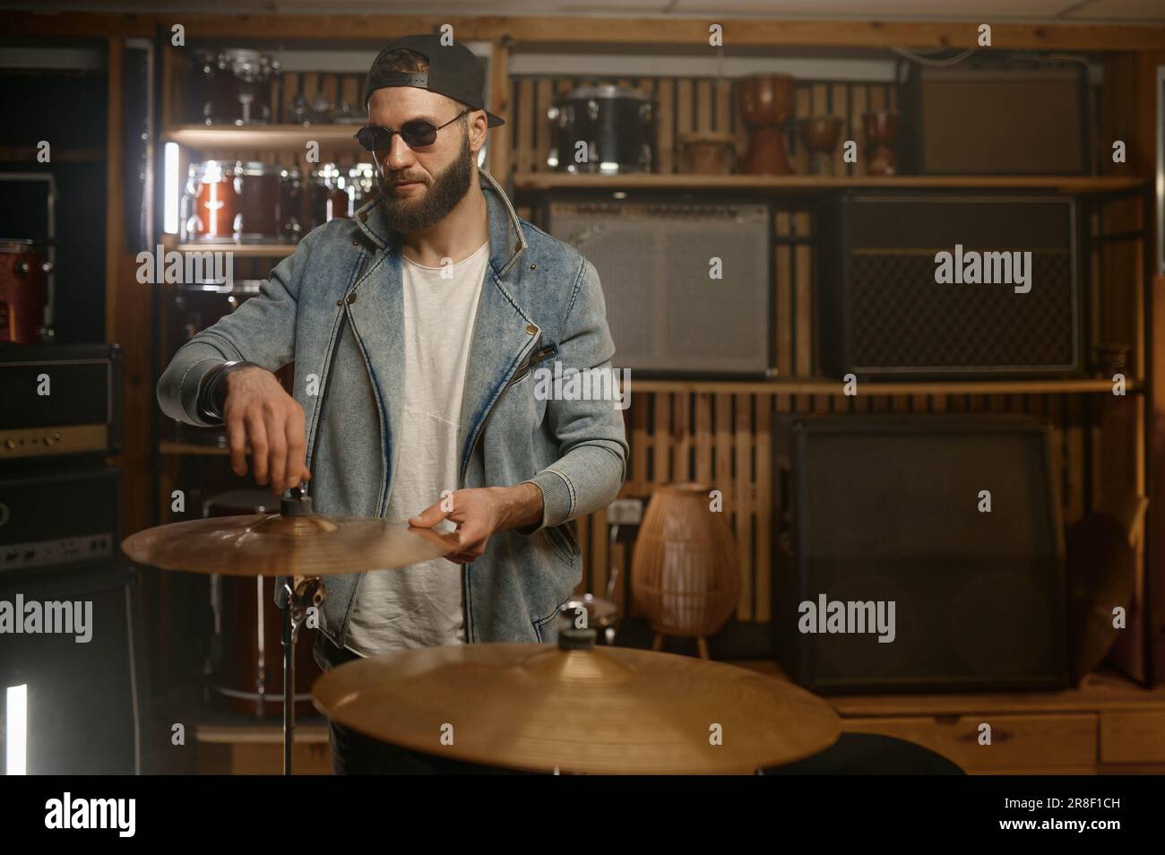 Handsome drummer standing nearby drum set with metallic gold plate Stock Photo