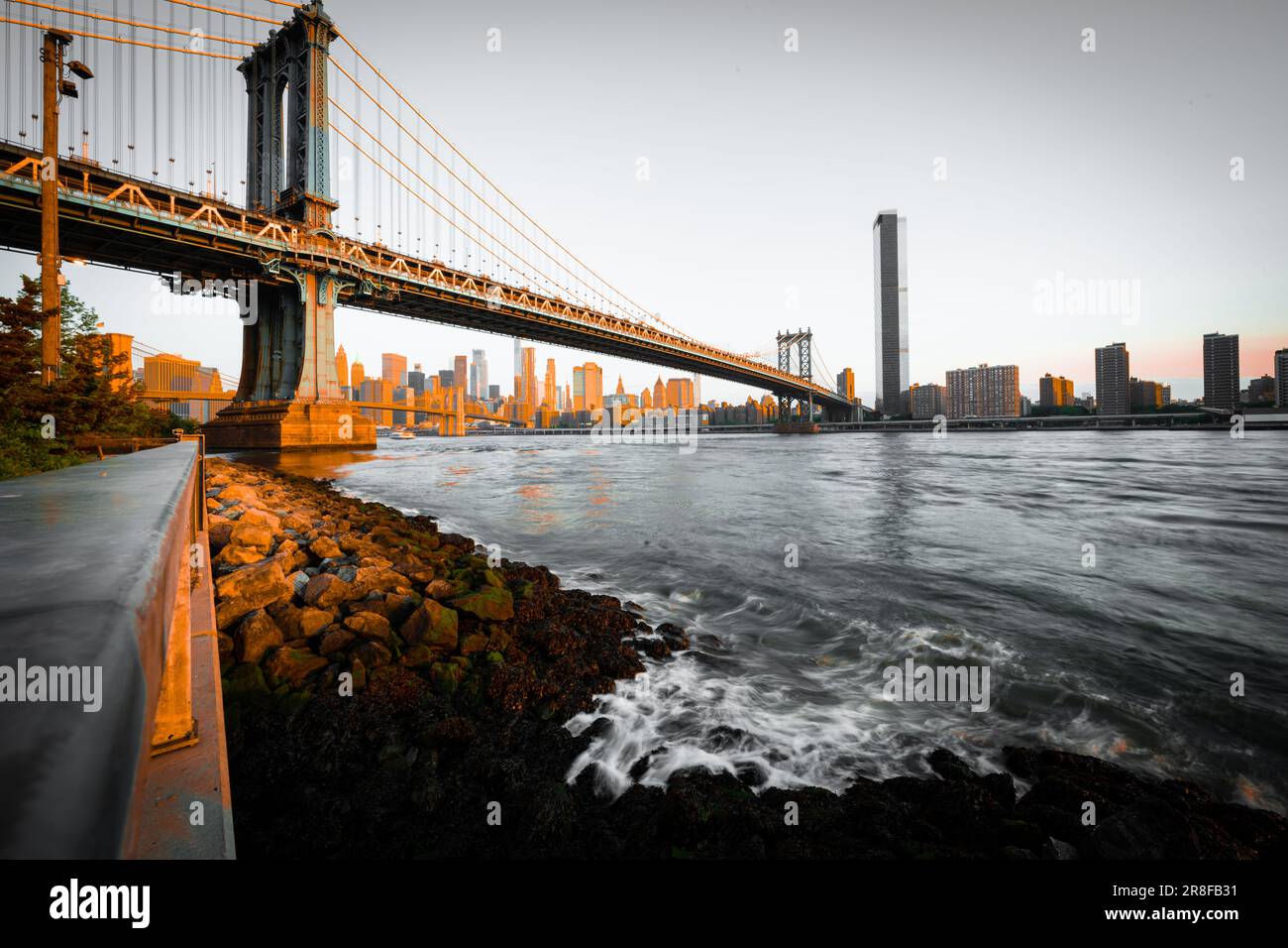 A scenic view from the bank of a river to the Manhattan Bridge. Stock Photo