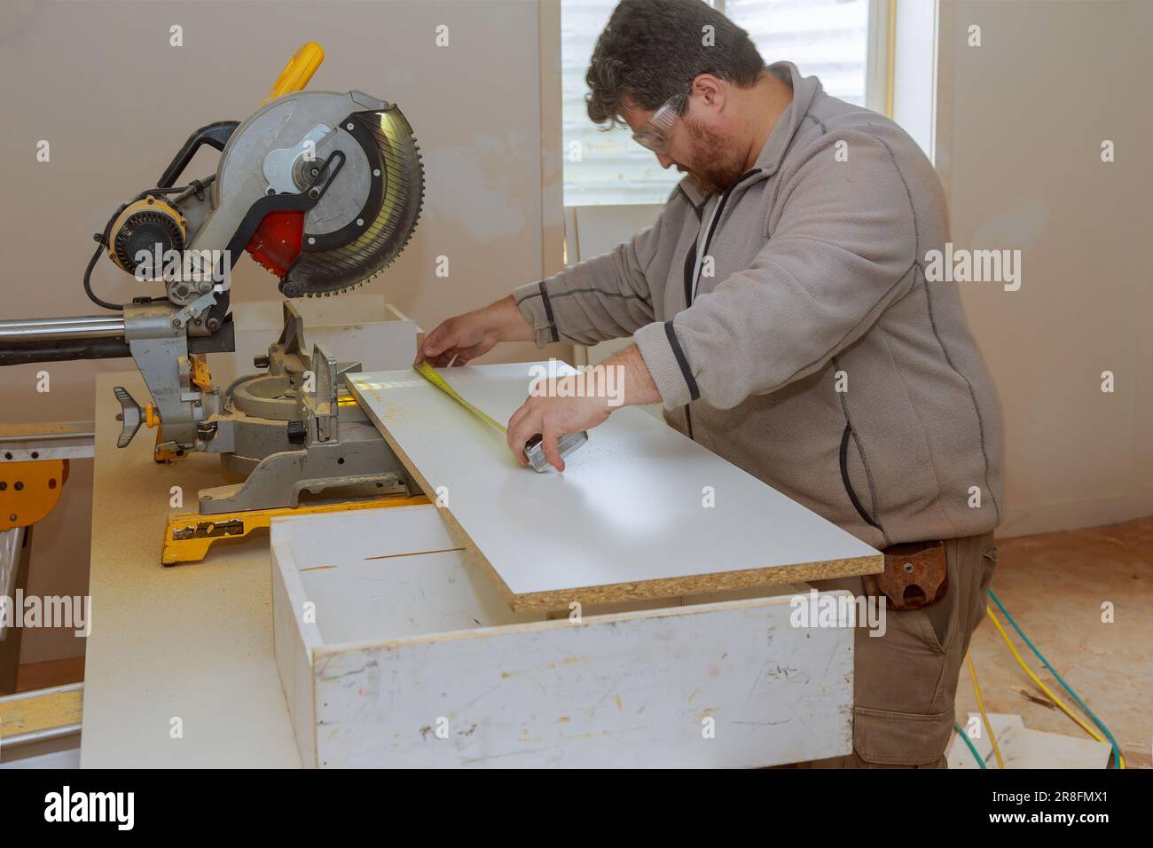 An employee uses circular saw to cut melamine board for shelves with