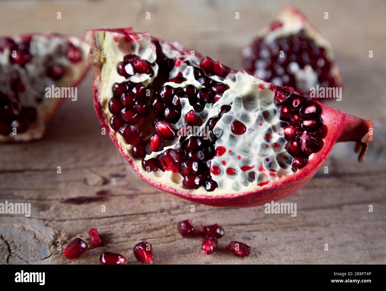 Pomegranate with seeds on brown wooden board Stock Photo