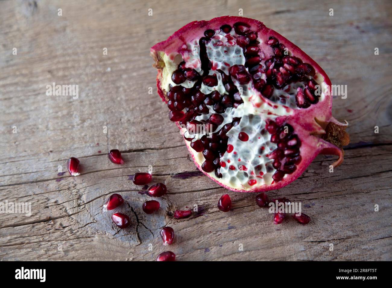 Pomegranate with seeds on brown wooden board Stock Photo
