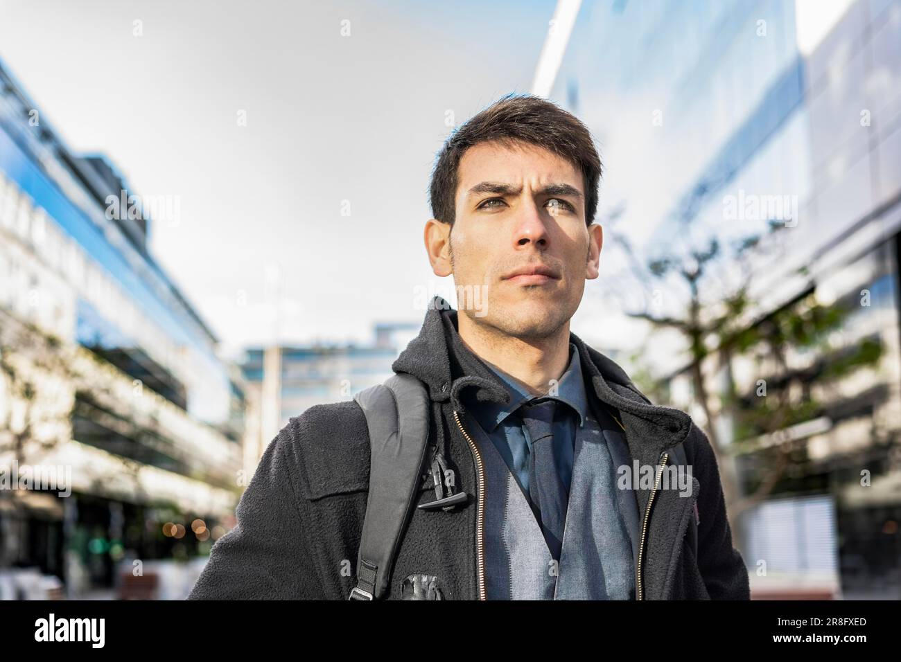 Low-angle view of an attractive businessman with his backpack on looking away while walking from his office Stock Photo