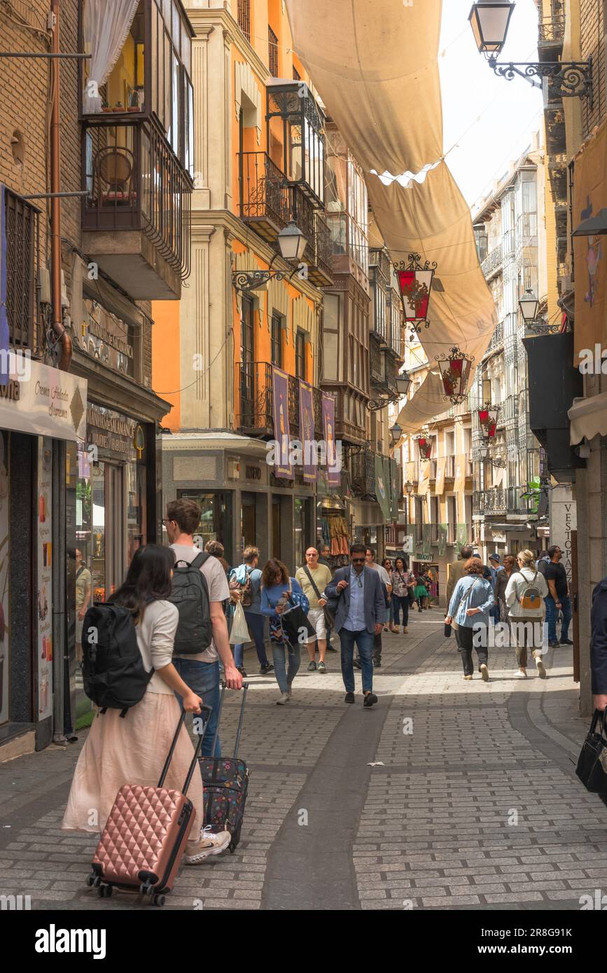 Vacation Spain, rear view in summer of two young people wheeling their suitcases in the Calle Commercio in the historic Old Town area of Toledo, Spain Stock Photo