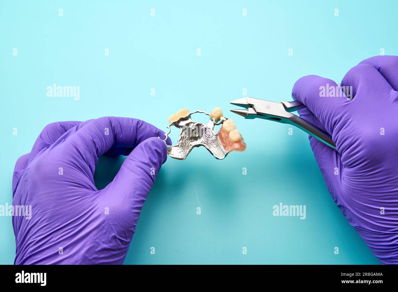 Dental technician making a denture, on a green workbench Stock Photo