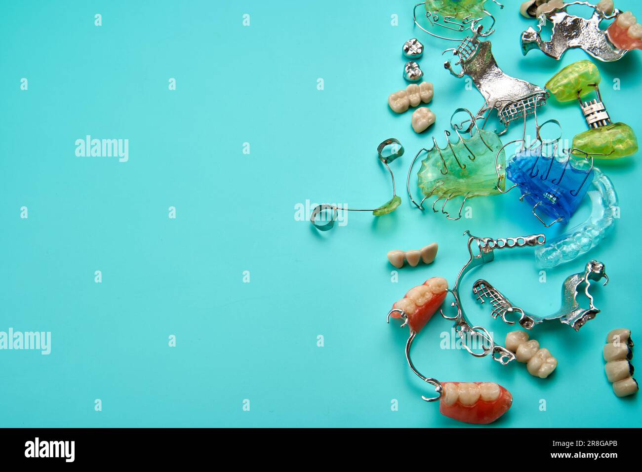 Different orthodontic appliances in many colors on top of a green table