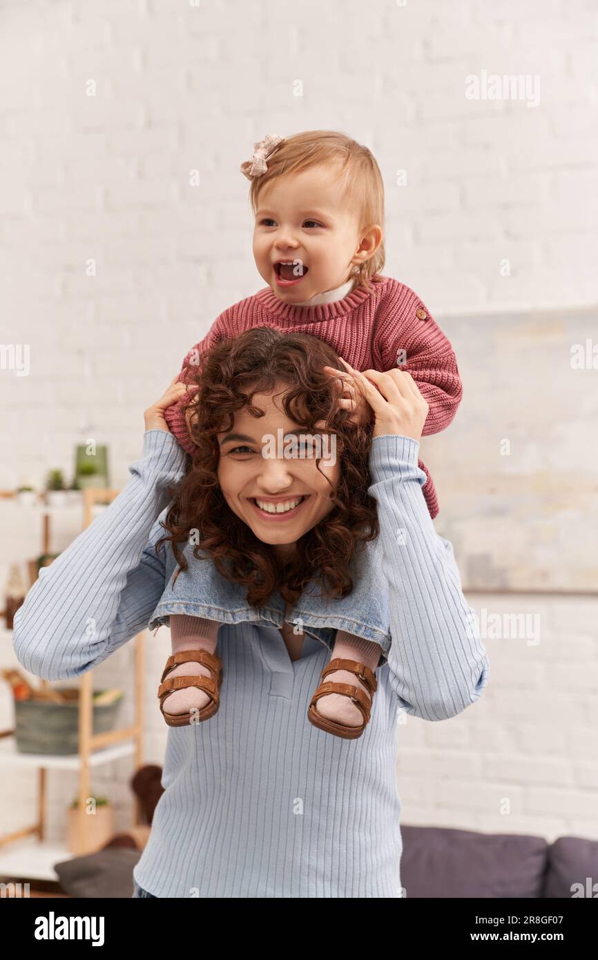cheerful woman with baby girl on shoulders, balanced lifestyle, mom daughter time, having fun together, quality time, work and life harmony, loving mo Stock Photo