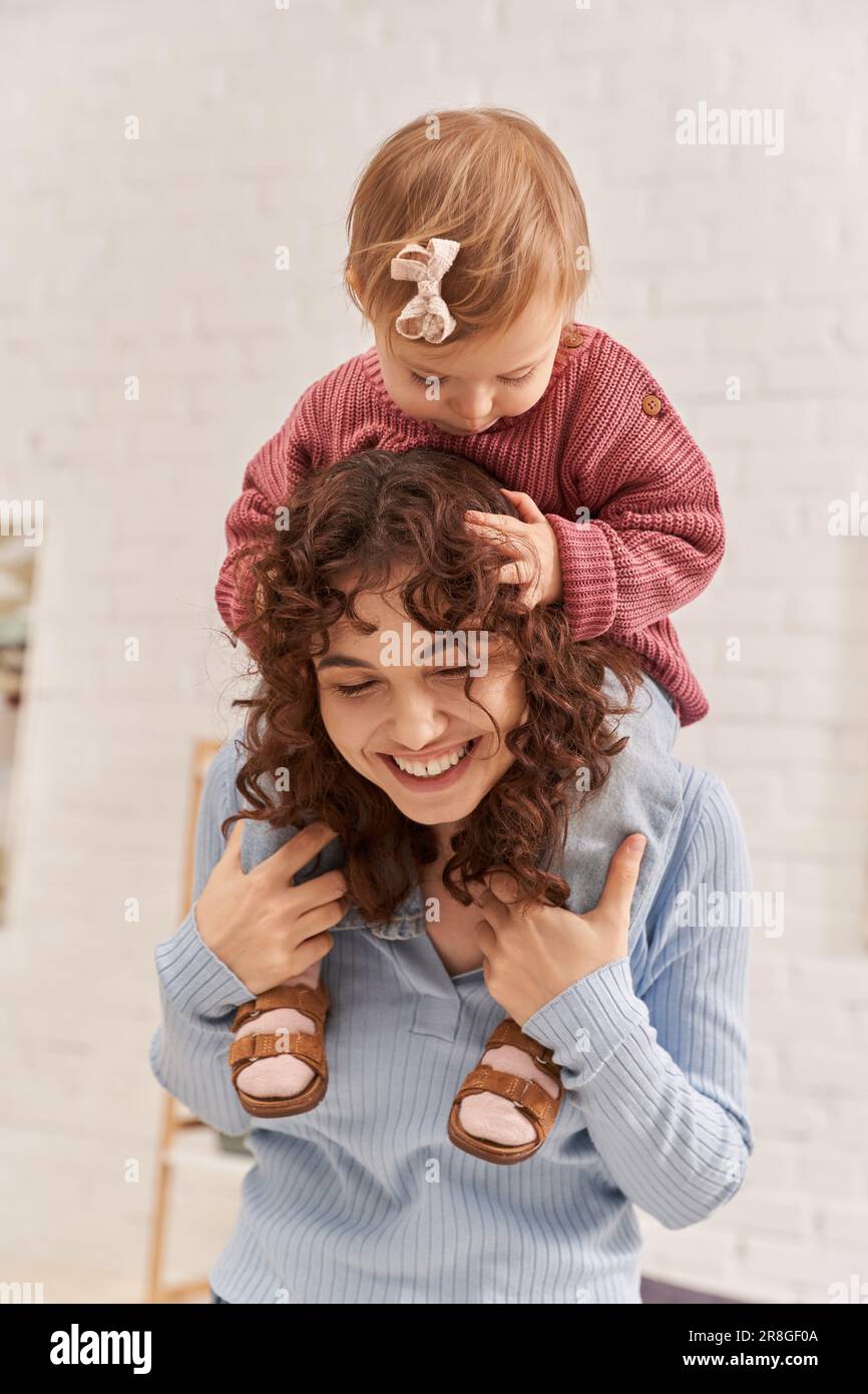 smiling woman with baby girl on shoulders, balanced lifestyle, mom daughter time, having fun together, quality time, work and life harmony, loving mot Stock Photo