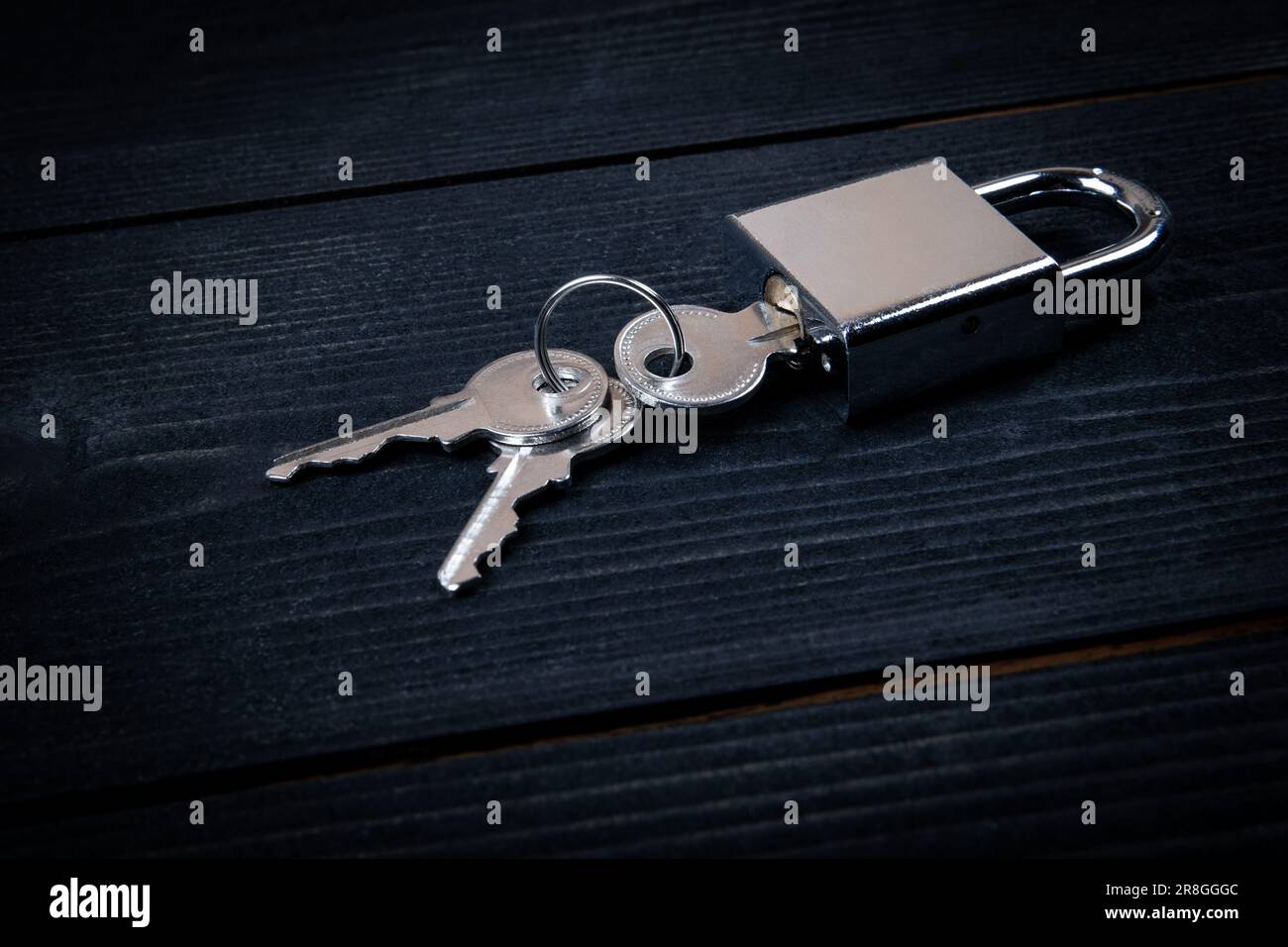 Padlock with three keys on dark wood texture background. Stock Photo