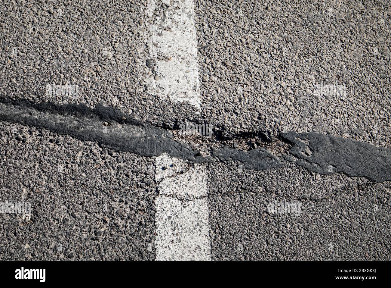 Damaged and potholed asphalt pavement. Danger and traffic safety. Sunny Day. Stock Photo