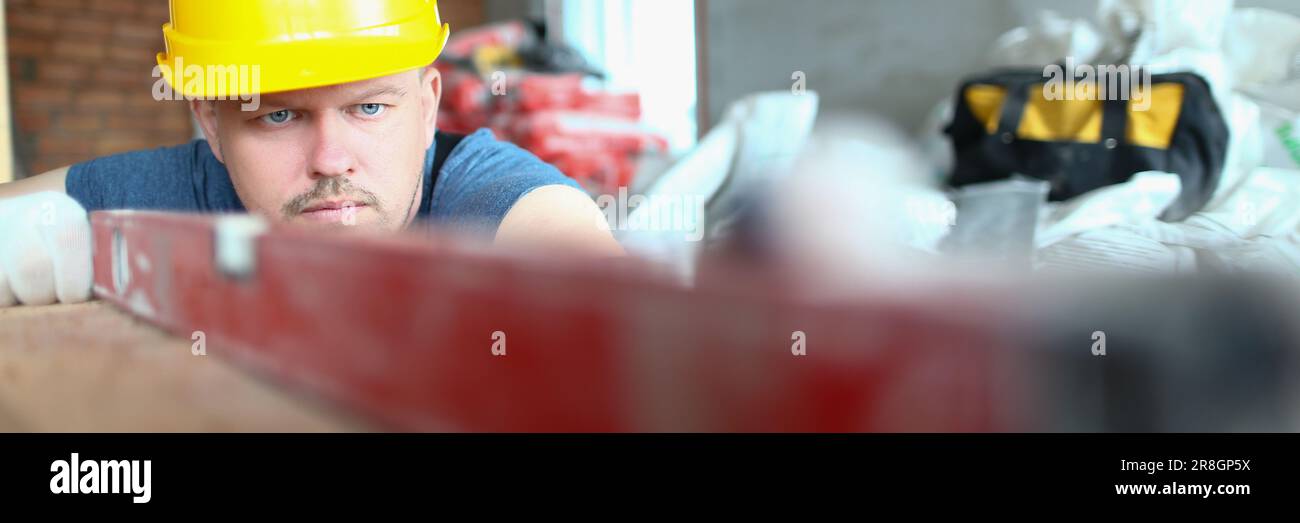 Bricklayer checks evenness of brick wall, brick foundation using spirit level Stock Photo