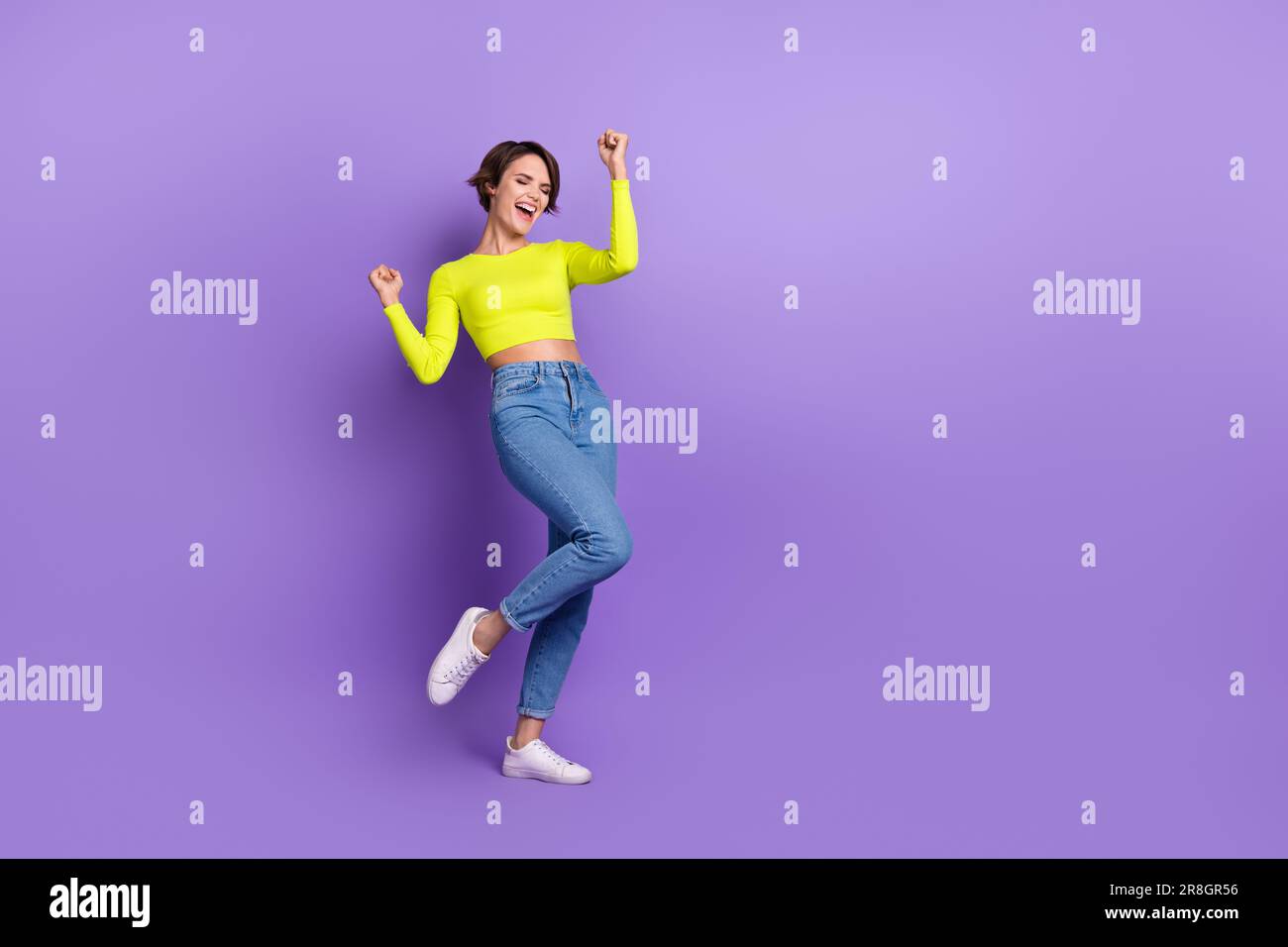Full body photo of crazy young lady wearing levis jeans calvin klein crop top celebrating summer sale isolated on purple color background Stock Photo
