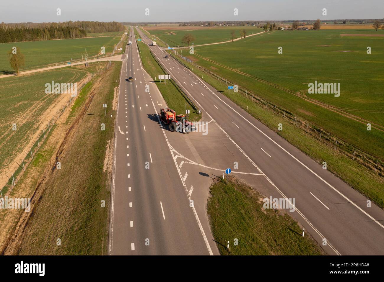 Drone photography of tractor with agricultural equipment driving on a road during spring day. Stock Photo