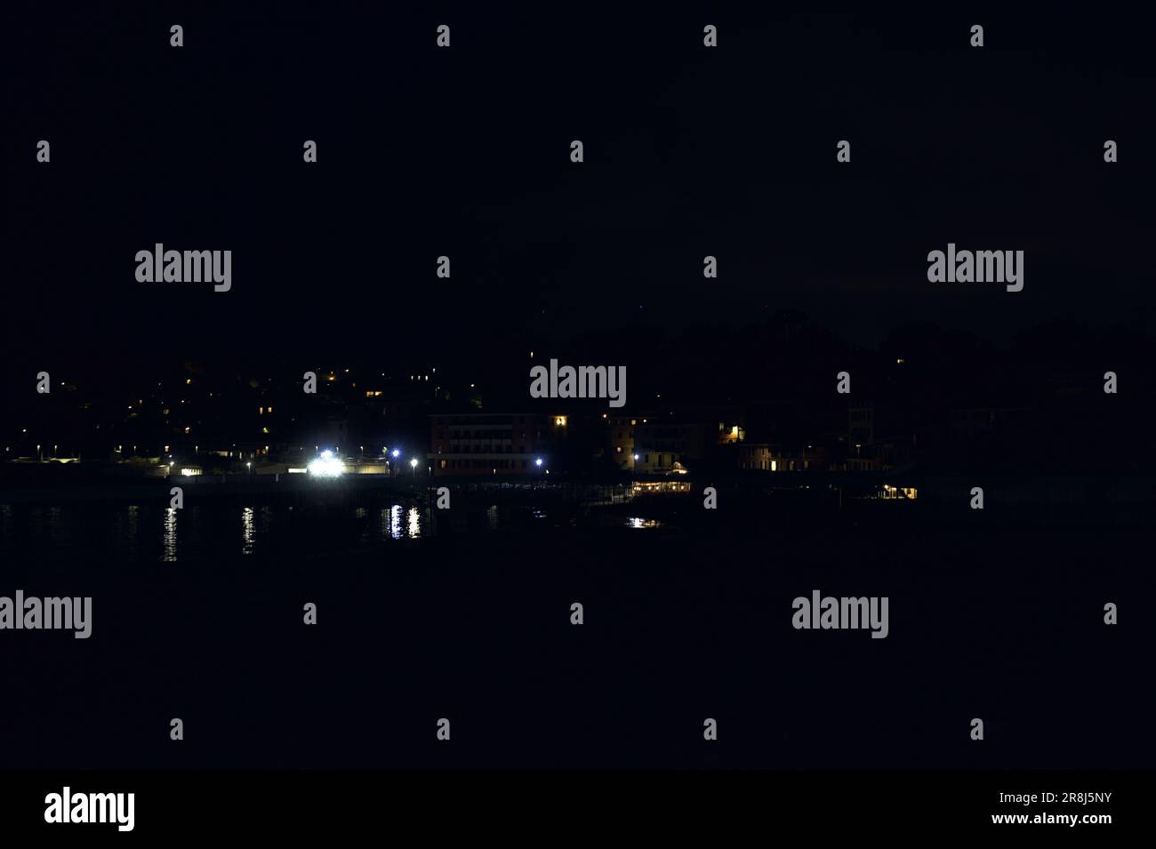 Town on a cliff by the sea at night seen from a beach afar Stock Photo ...