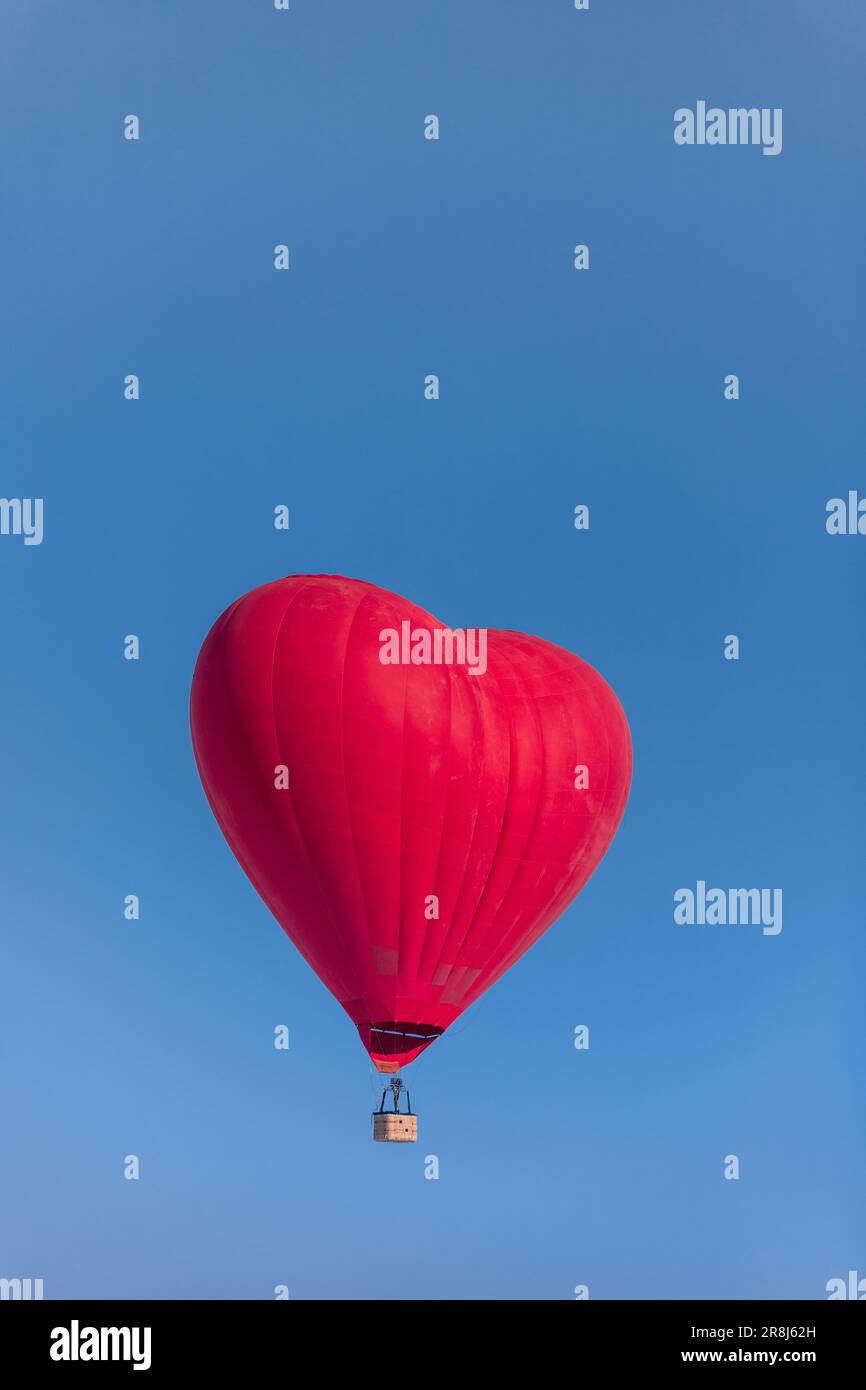 Hot air balloon in the shape of a red heart against a clear blue sky, a ...