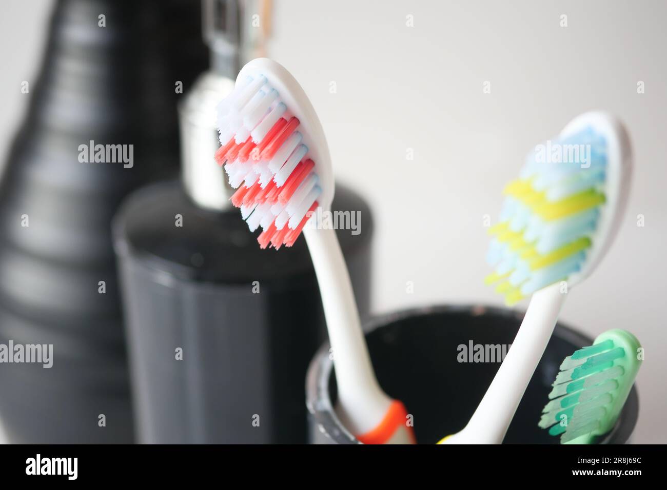 colorful toothbrushes in white mug against a wall Stock Photo - Alamy