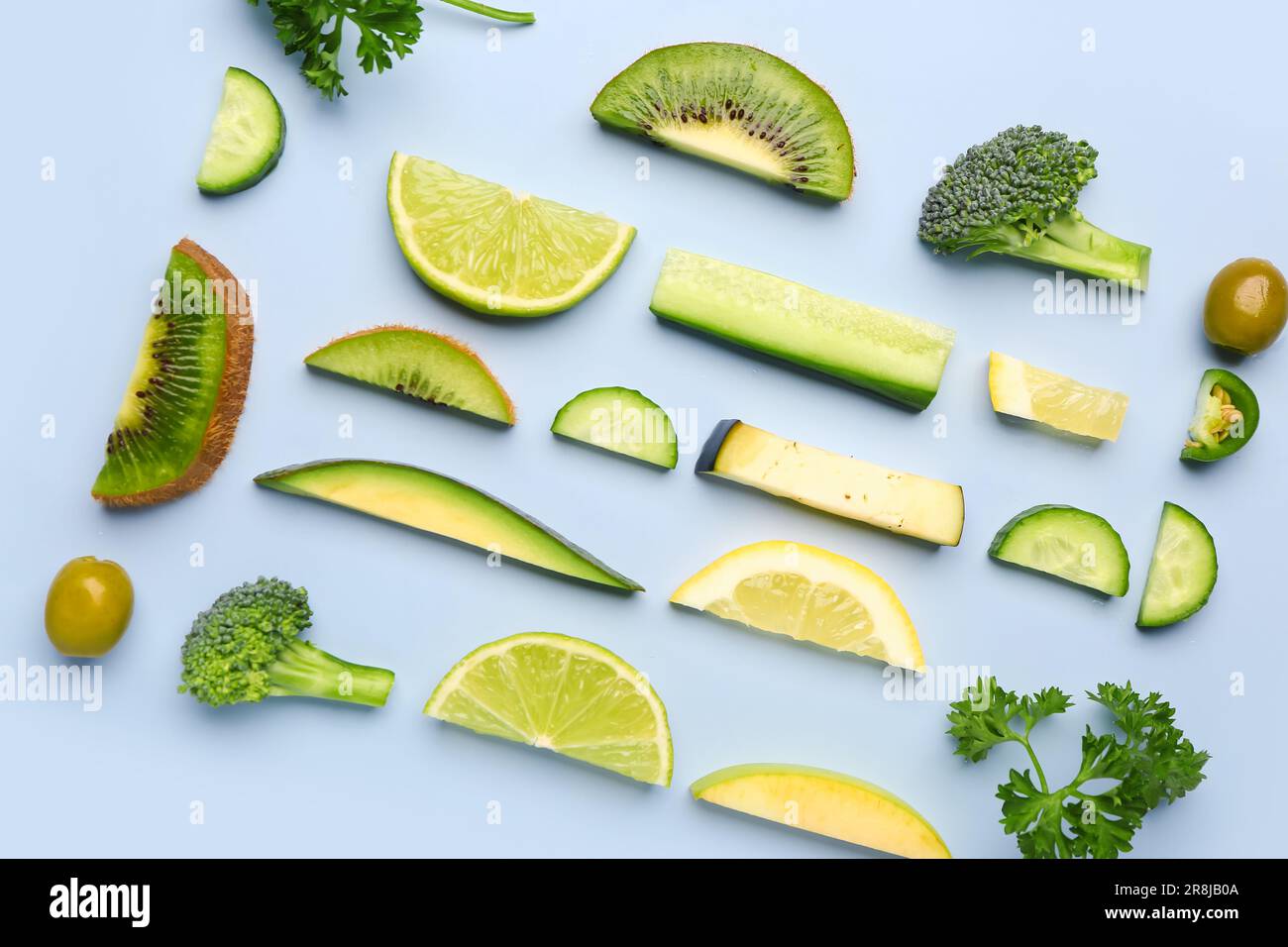 Composition with green fresh fruits and vegetables on blue background ...