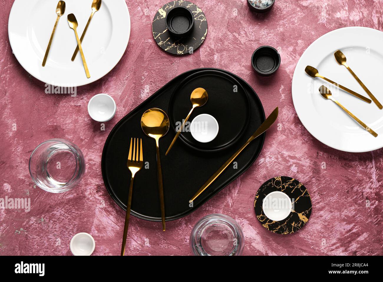 Clean plates with set of golden cutlery on dark pink table Stock Photo ...