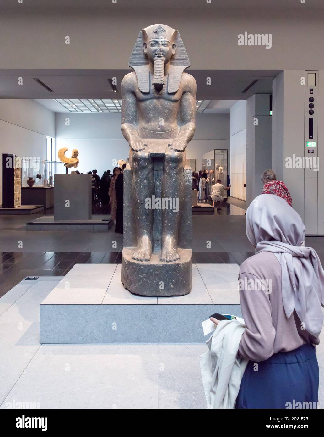 A woman looks at an Ancient Egyptian statue in the Louvre Museum, Abu