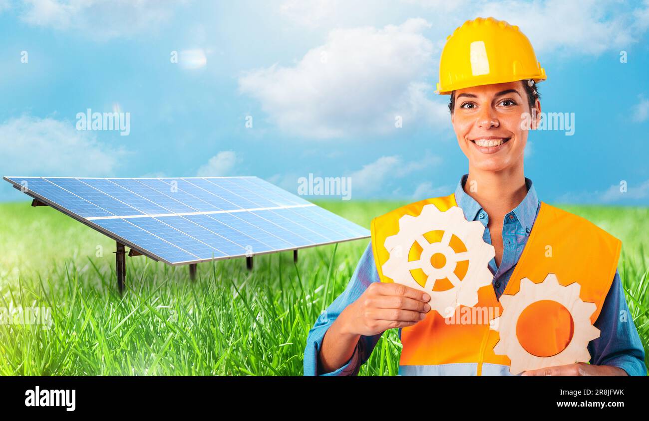 Woman holds two pieces of gears against in front of a solar panel Stock Photo