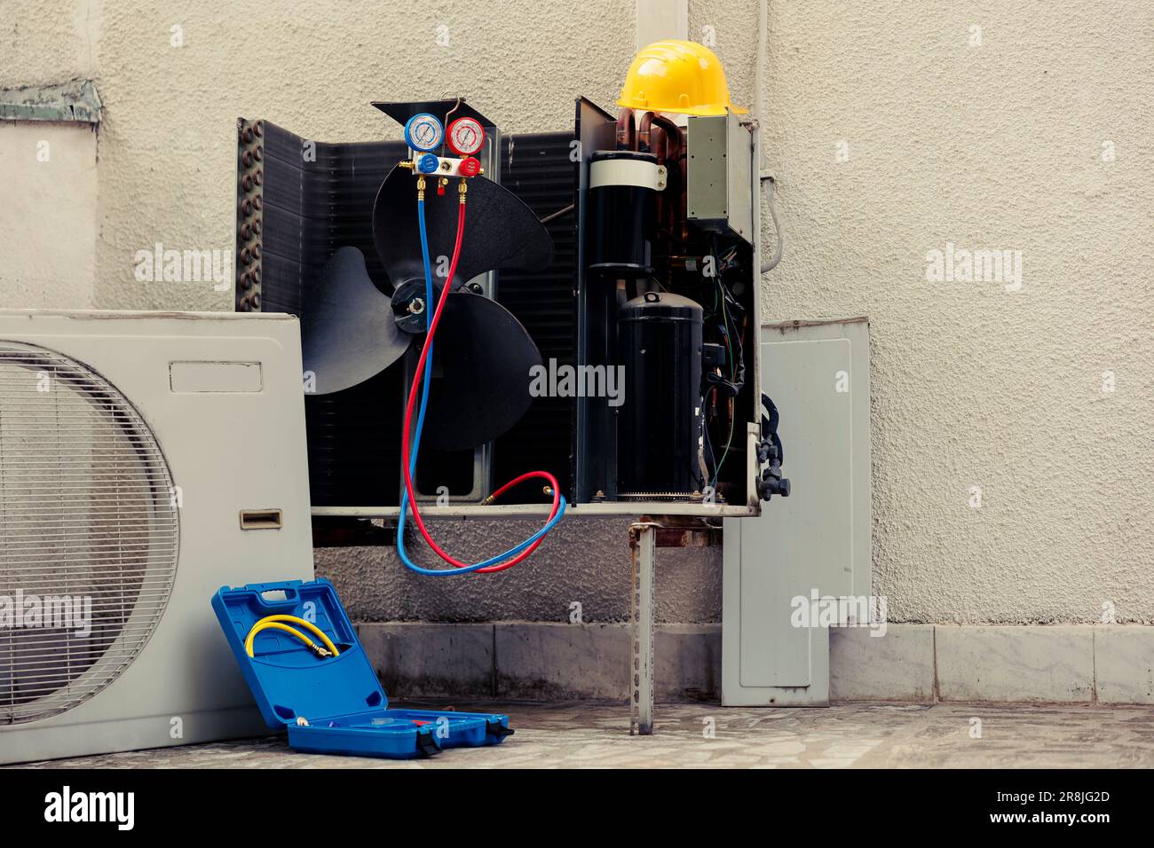 Broken external air conditioner unit with protection cover removed in need of repair, with