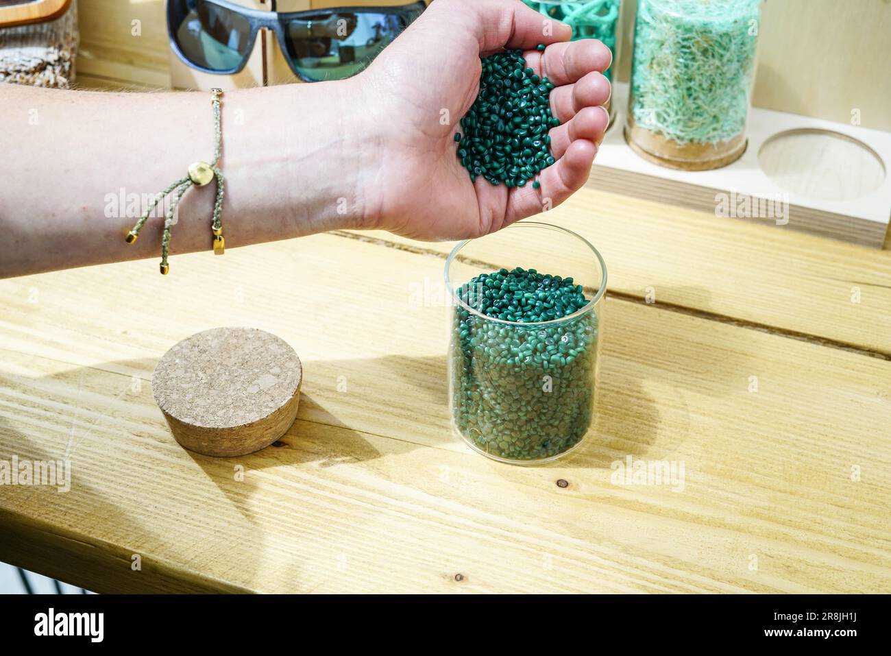 A person's hand seen pouring recycled plastic pellets from abandoned
