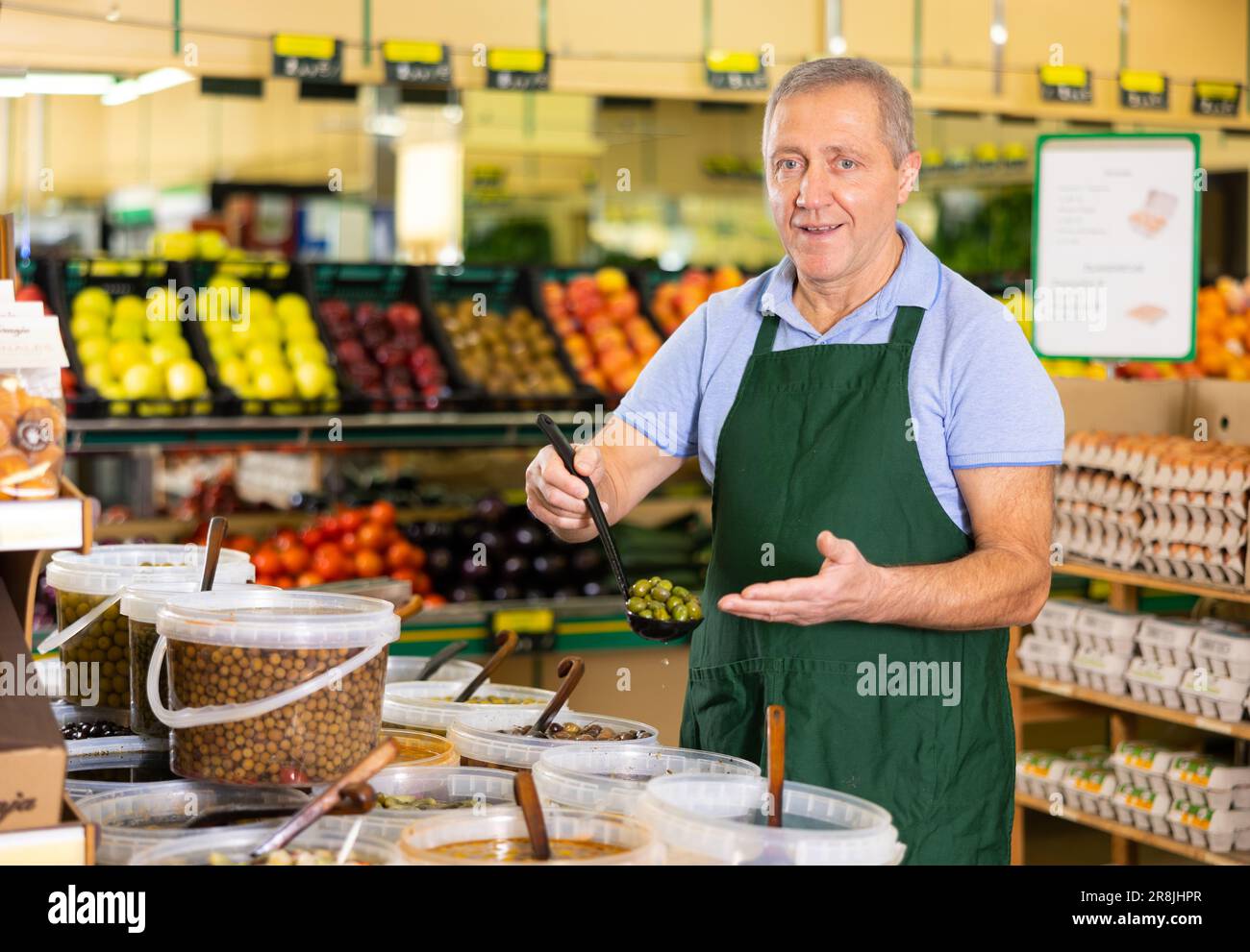 Elderly salesman showing olives in grocery store Stock Photo Alamy