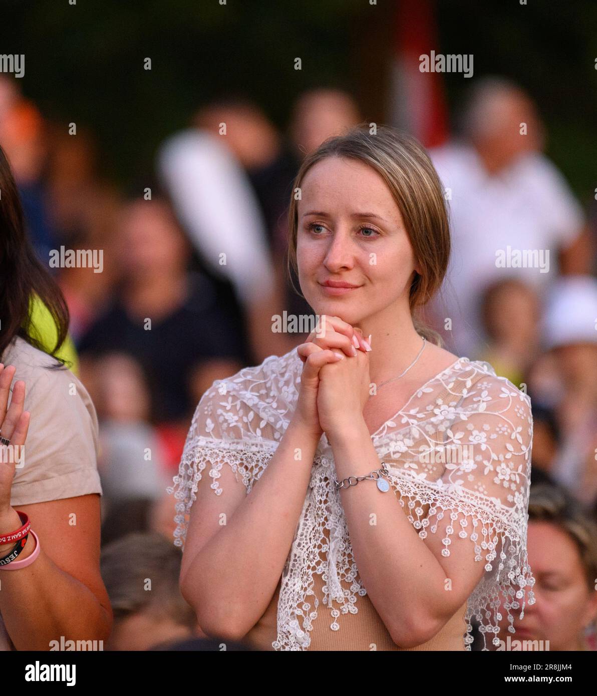 A young girl praying in the midst of many other pilgrims during Mladifest 2022 – the youth festival – in Medjugorje. Stock Photo