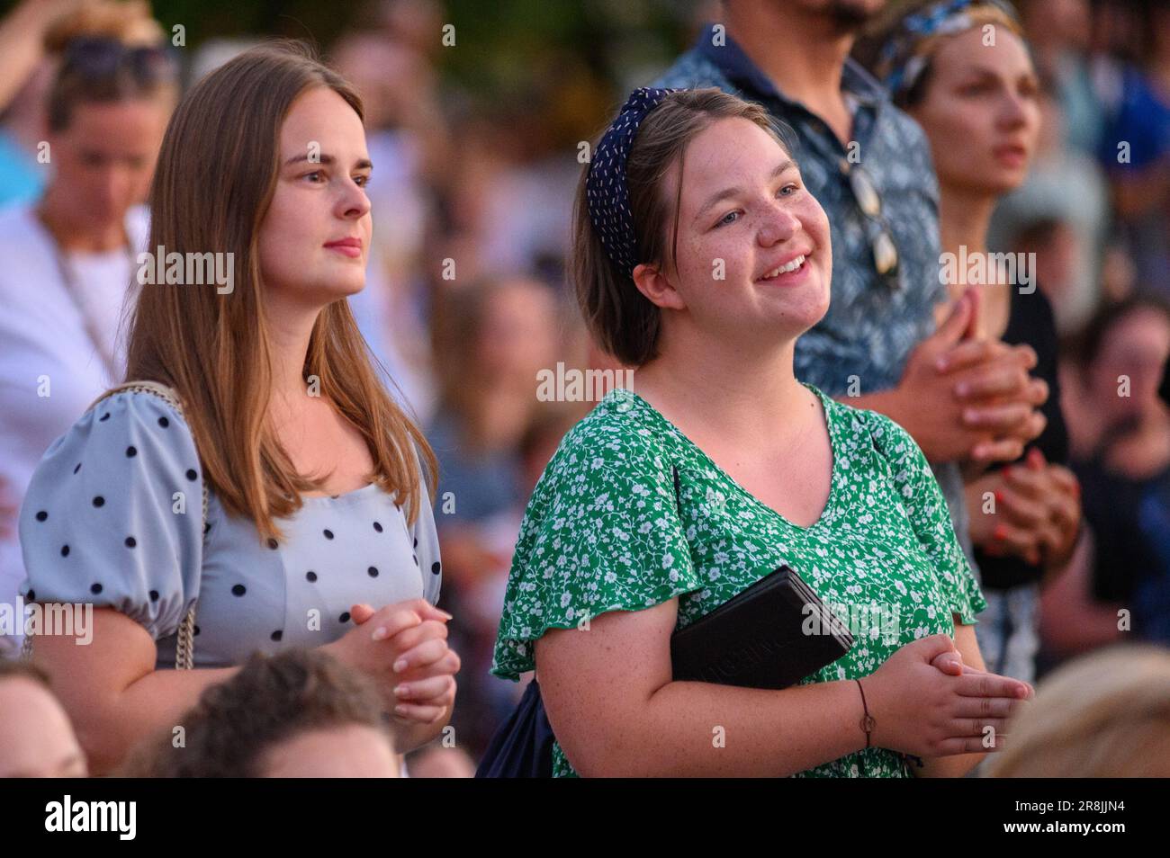 Young girls praying in the midst of many other pilgrims during Mladifest 2022 – the youth festival – in Medjugorje. Stock Photo