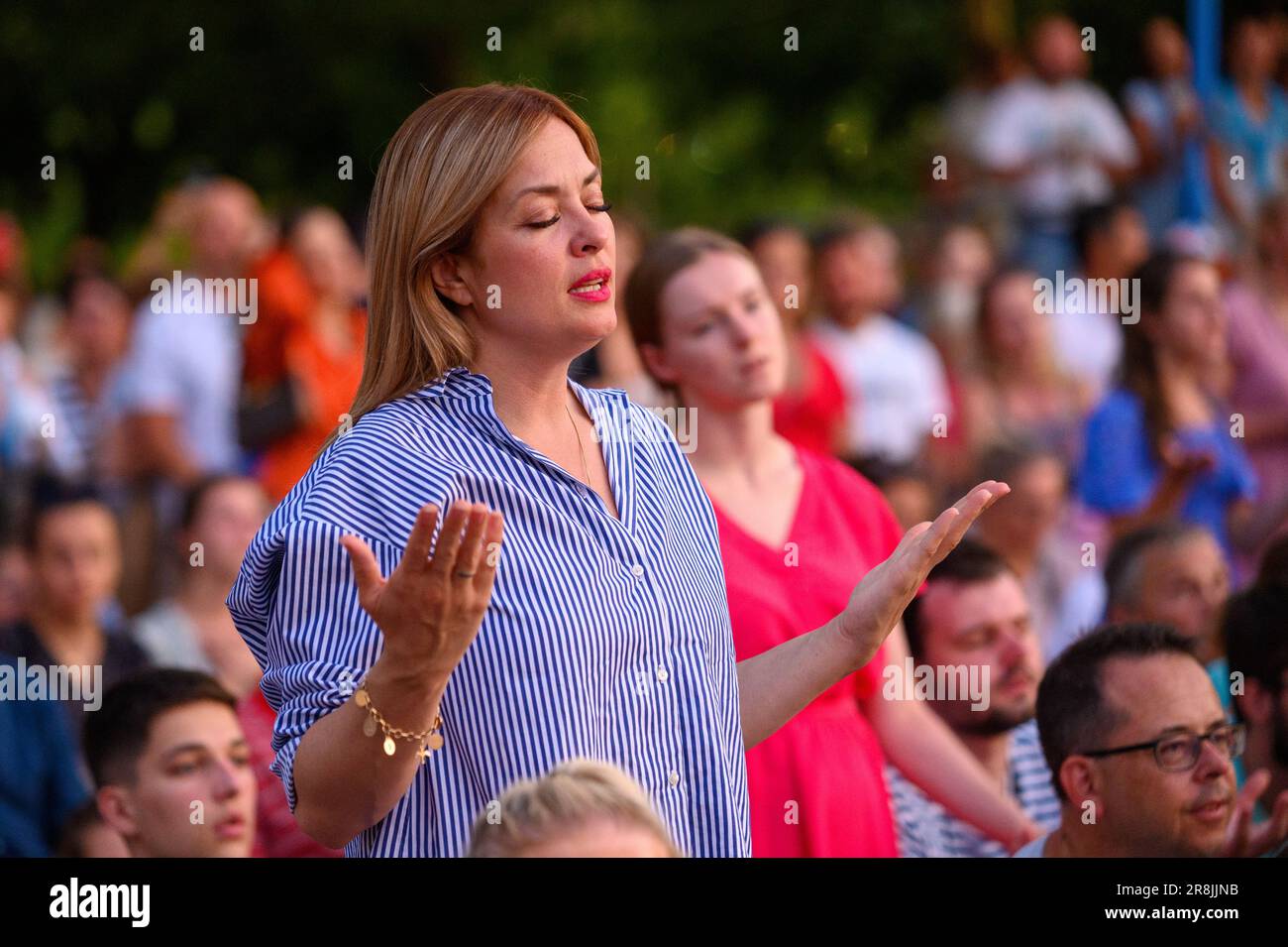 A woman praying and singing in the midst of many other pilgrims during Mladifest 2022 – the youth festival – in Medjugorje. Stock Photo