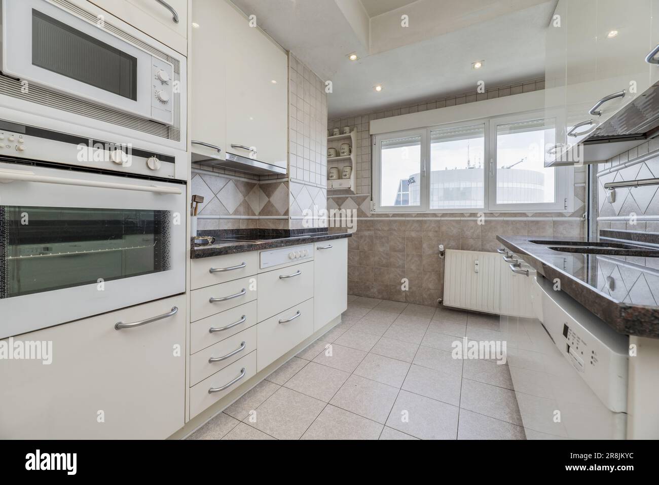 View of Large kitchen with cabinets on both sides of the walls, polished ...