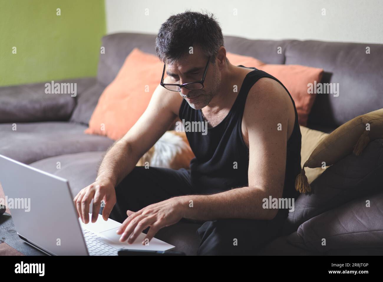 Contemporary image of a middle-aged man with dark hair working from home, his face reflecting determination and focus as he uses his laptop Stock Photo