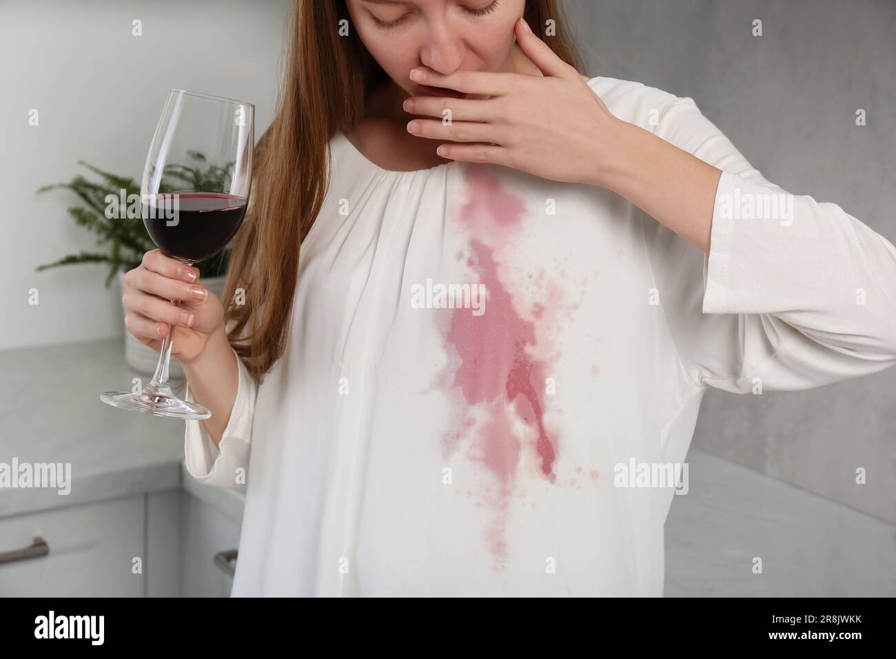 Embarrassed woman with wine stain on her clothes and glass of wine