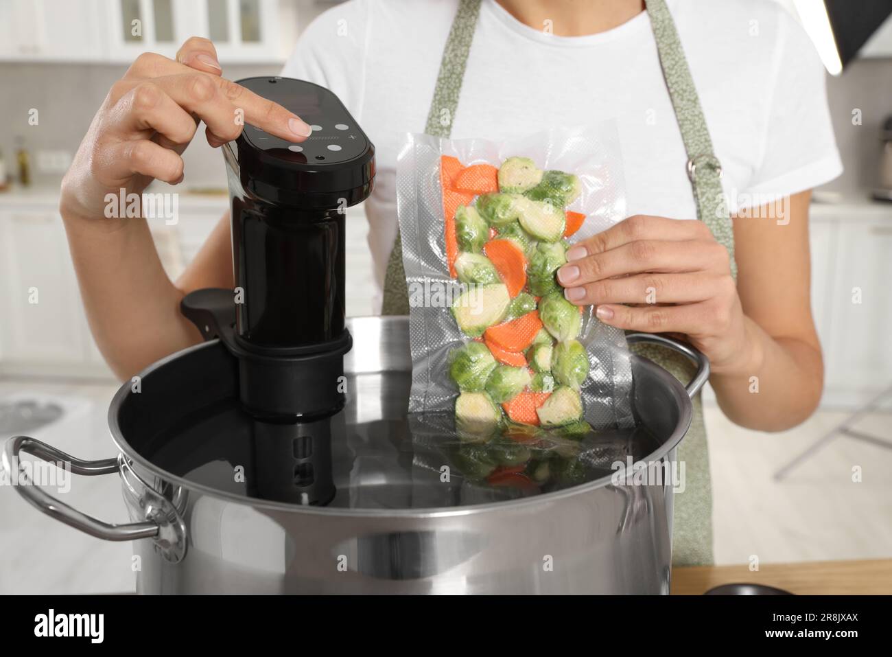 Woman putting vacuum packed vegetables into pot and using thermal