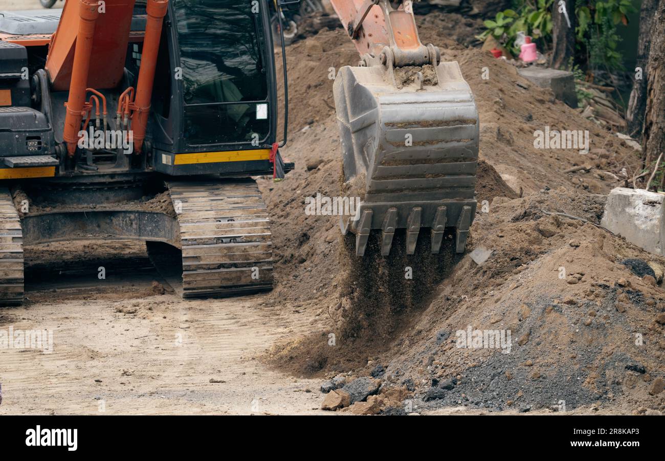 Backhoe working by digging soil at construction site. Bucket teeth of