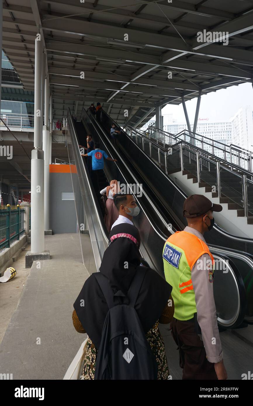 you can see train security giving directions to train passengers near the escalator, with a busy atmosphere Stock Photo