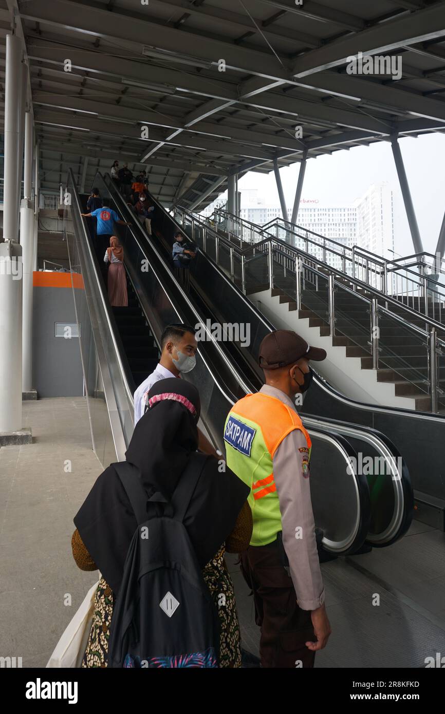 you can see train security giving directions to train passengers near the escalator, with a busy atmosphere Stock Photo