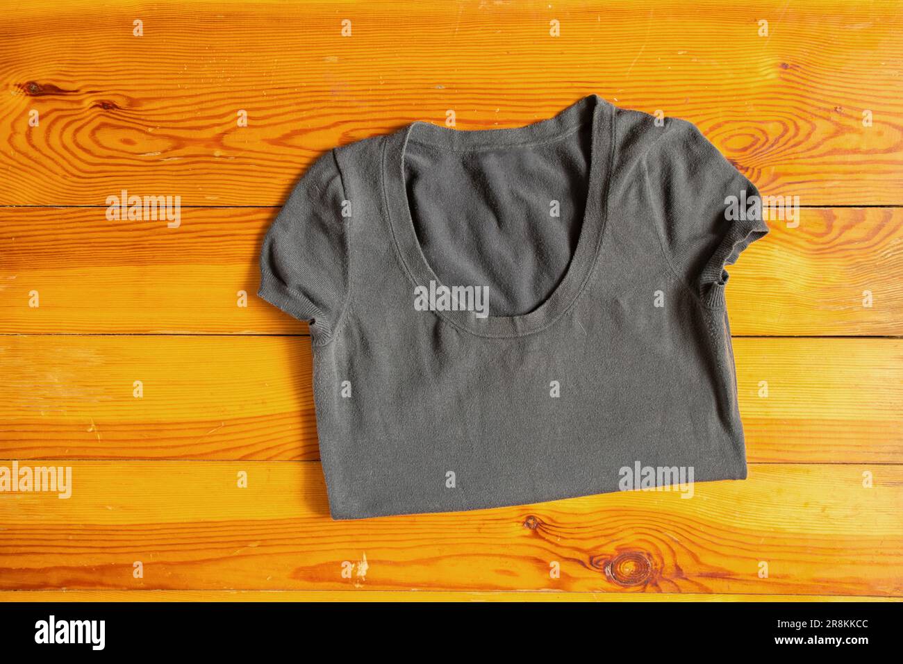 gray women's T-shirt lies on a wooden table close-up Stock Photo