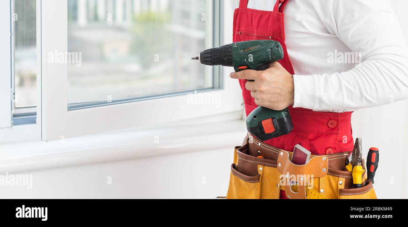 Young worker repairing window in flat. Stock Photo