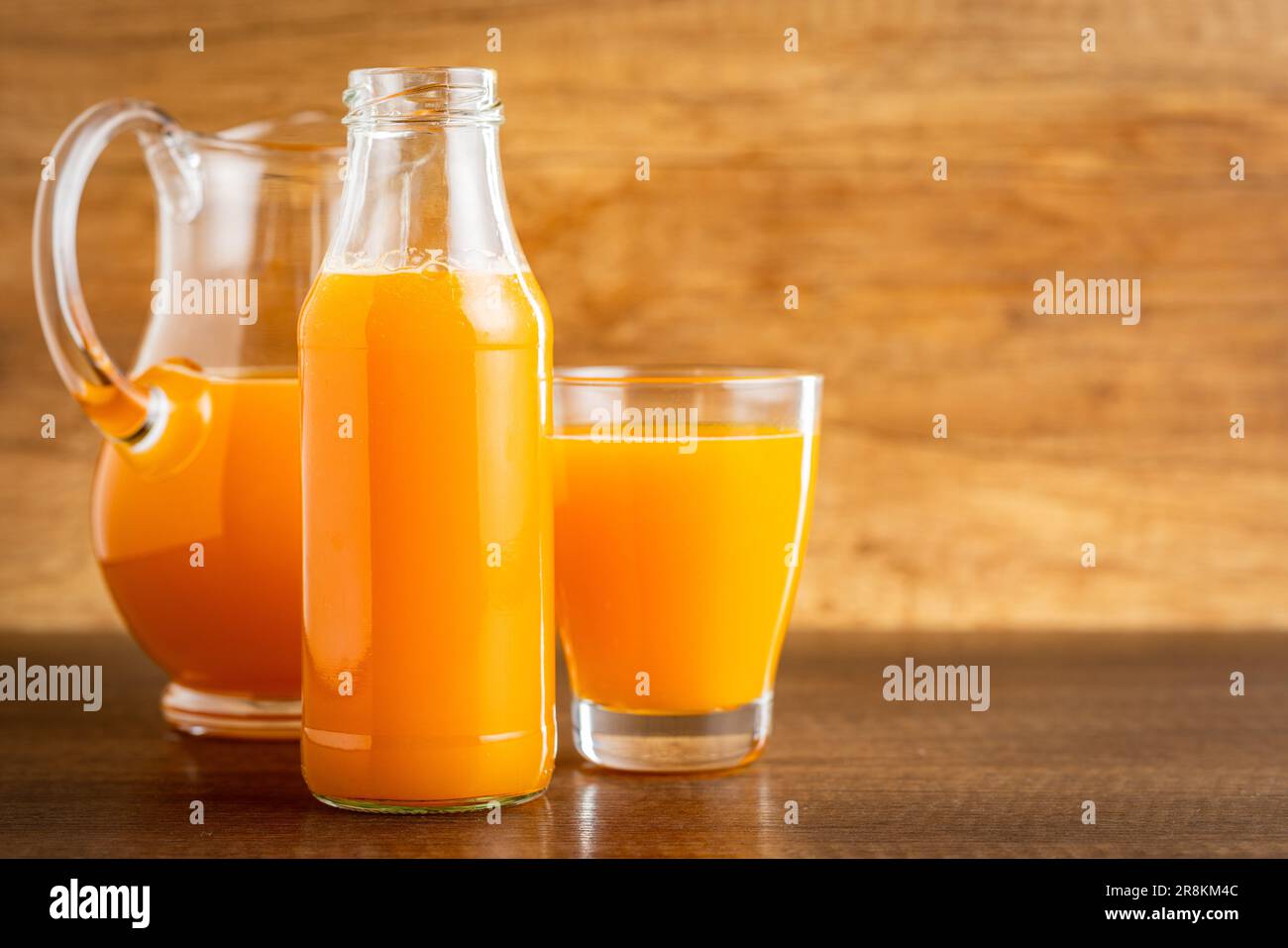 A glass bottle of fruit juice. Orange  juice on the wooden table. Stock Photo