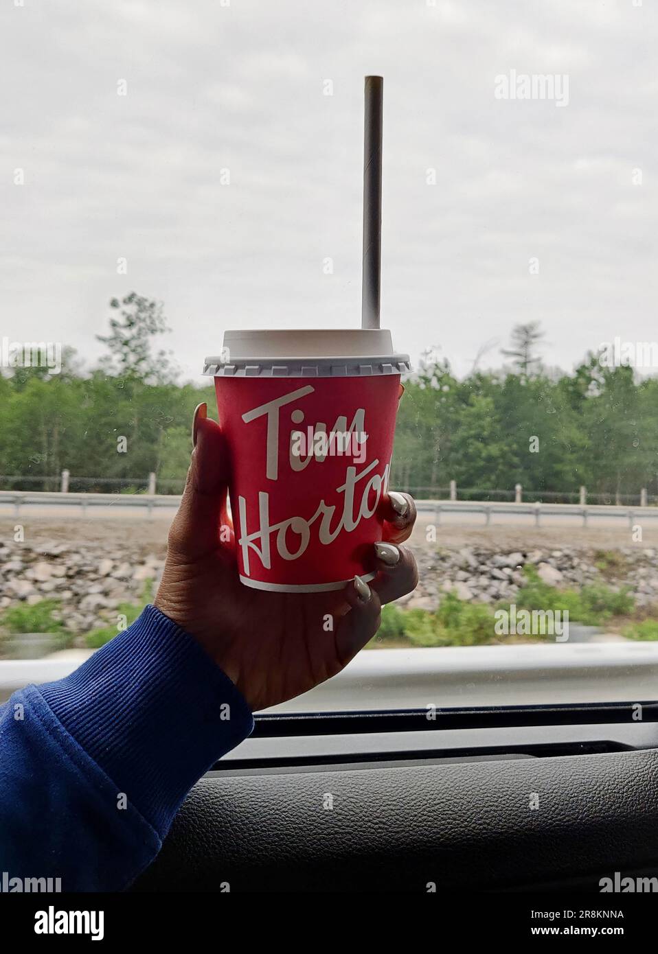 A young girl holding Tim Hortons coffee mug while travelling in a car Stock Photo