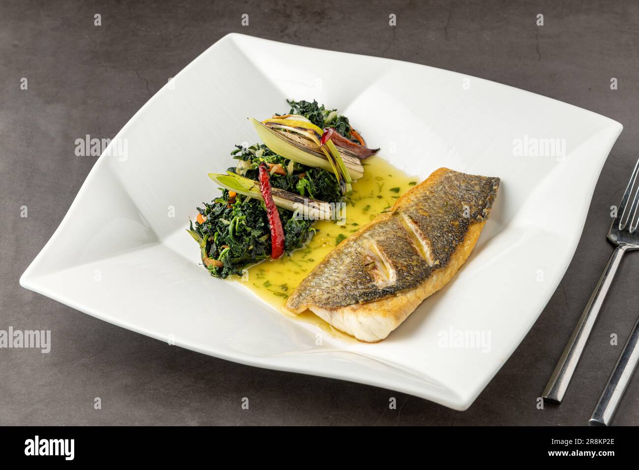 Grilled sea bass fillet served with garnishes in a fine dining restaurant Stock Photo