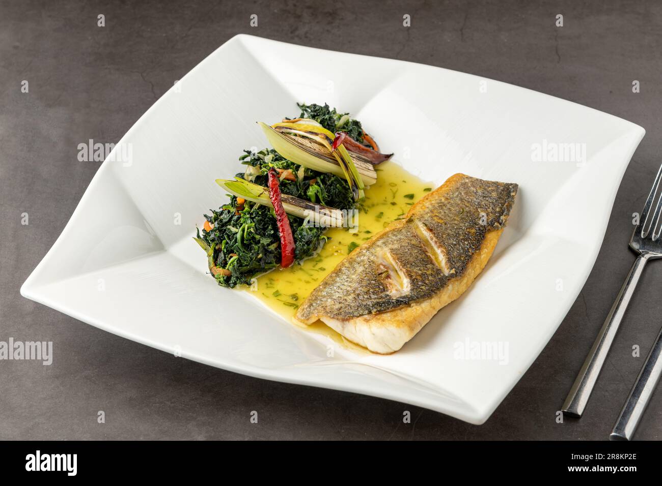Grilled sea bass fillet served with garnishes in a fine dining