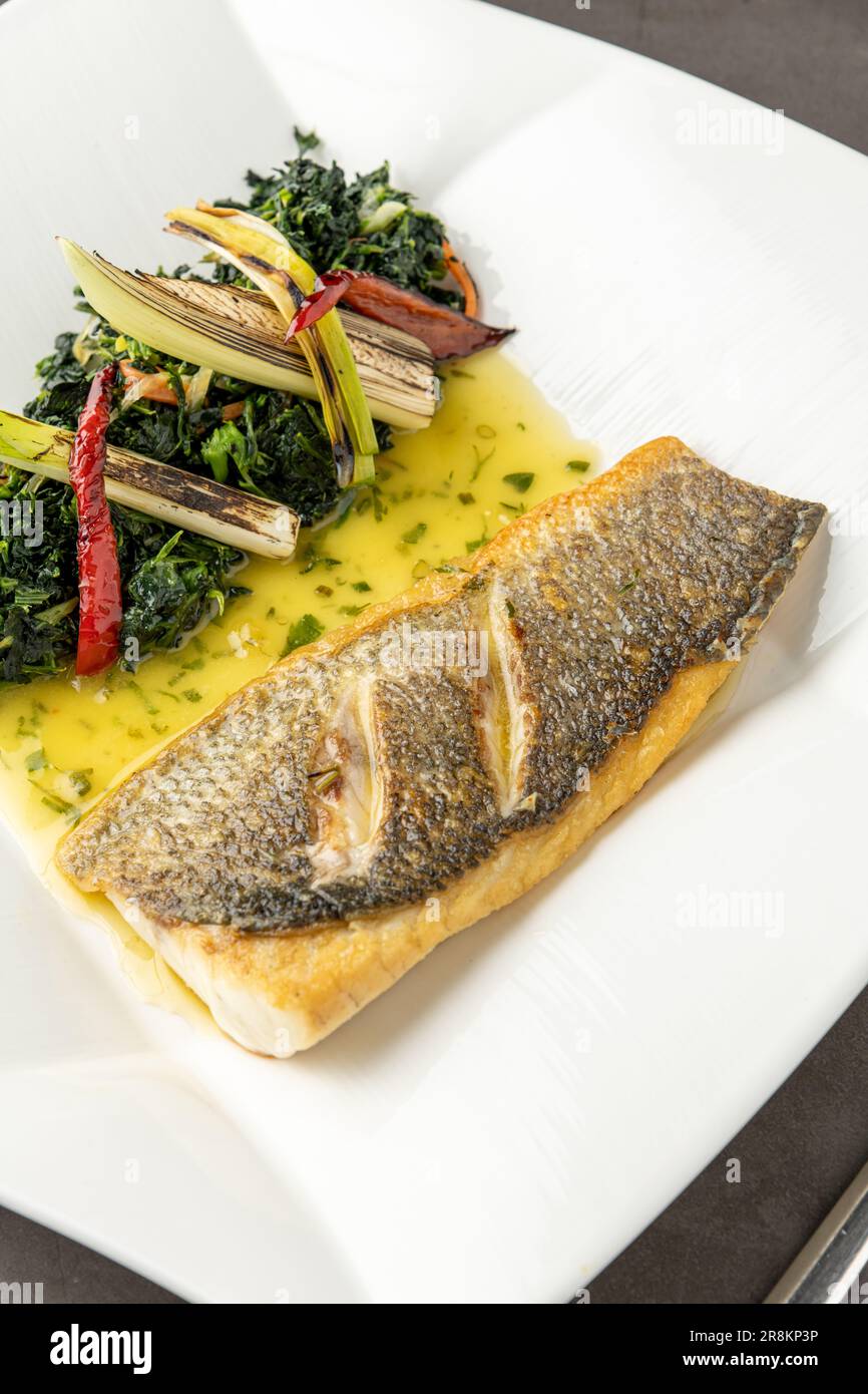 Grilled sea bass fillet served with garnishes in a fine dining