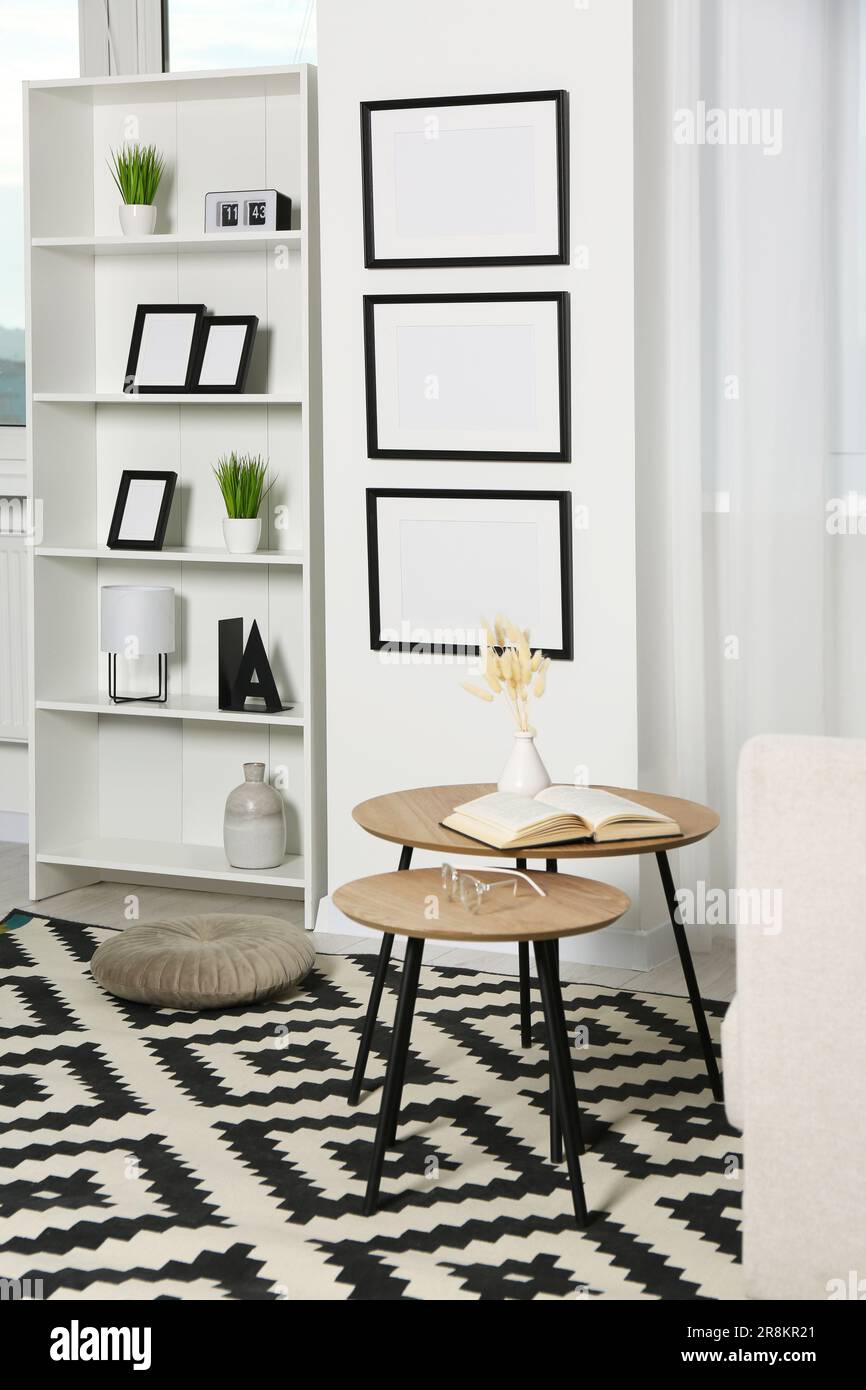 Stylish room interior with empty frames hanging on white wall near