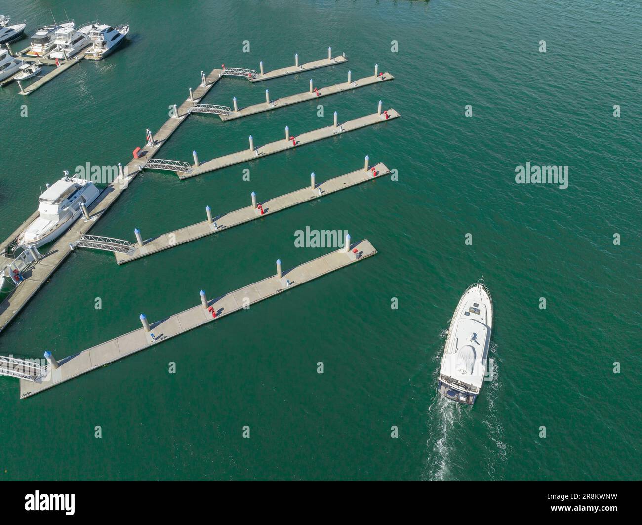 Aerial view of a lone cabin cruiser passing empty boating pontoons at Southport on the Gold Coast at Queensland in Australia Stock Photo